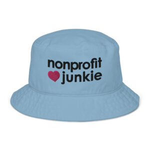 Slate blue bucket hat, black text on one side says nonprofit junkie in regular arial like font next to a pink heart