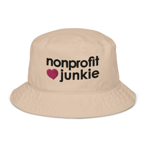 Beige bucket hat, black text on one side says nonprofit junkie in regular arial like font next to a pink heart