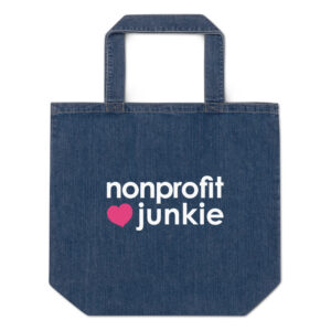 Organic denim tote bag, white text on one side says nonprofit junkie next to a pink heart