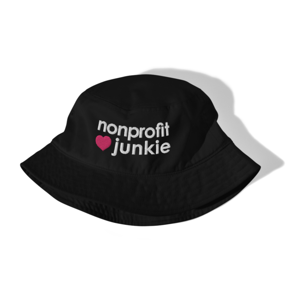 Black bucket hat, white text on one side says nonprofit junkie in regular arial like font next to a pink heart