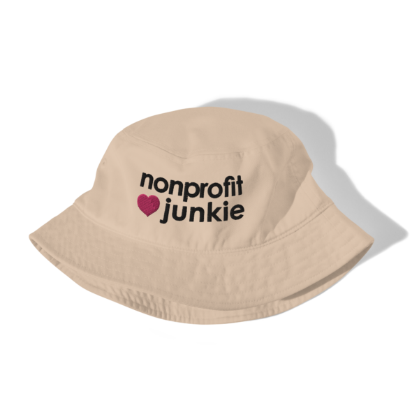 Beige bucket hat, black text on one side says nonprofit junkie in regular arial like font next to a pink heart