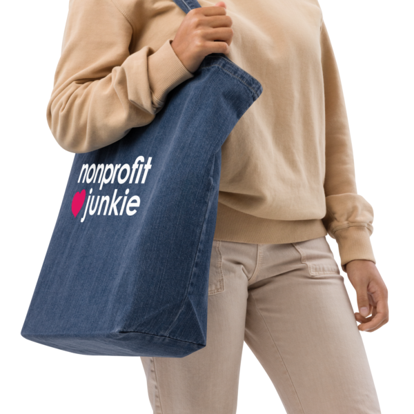 Organic denim tote bag, white text on one side says nonprofit junkie next to a pink heart