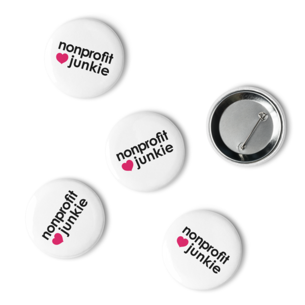 Set of white pin buttons, black text on one side says nonprofit junkie in regular arial like font next to a pink heart