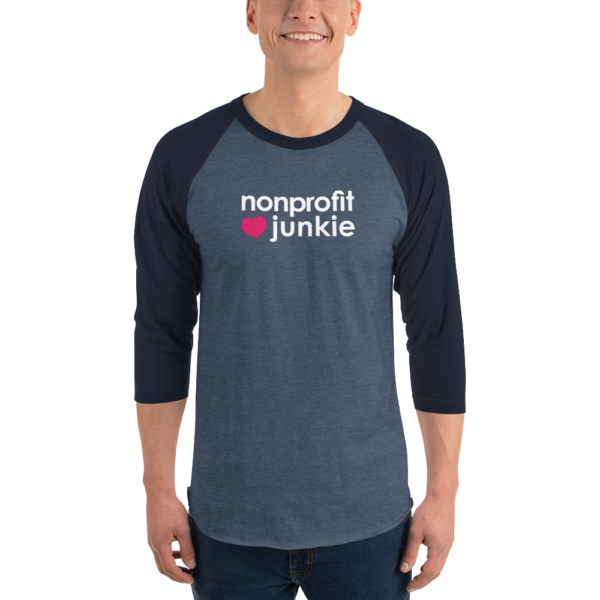 Navy 3 4th sleeve raglan shirt, heather denim in middle, white text on one side says nonprofit junkie next to a pink heart, on a man