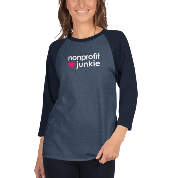 Navy 3 4th sleeve raglan shirt, heather denim in middle, white text on one side says nonprofit junkie next to a pink heart, on a woman