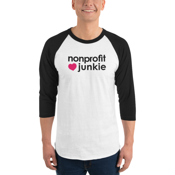 Black 3 4th sleeve raglan shirt, white in middle, black text on one side says nonprofit junkie next to a pink heart, on a man