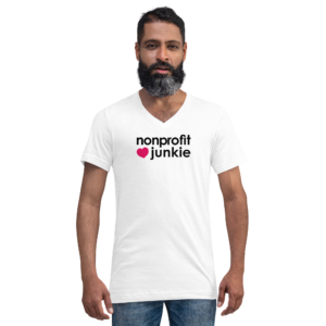 Unisex white v neck t shirt, black text on one side says nonprofit junkie in regular arial font next to a pink heart on a man