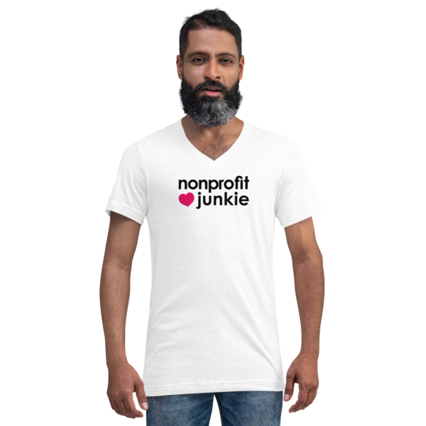 Unisex white v neck t shirt, black text on one side says nonprofit junkie in regular arial font next to a pink heart on a man