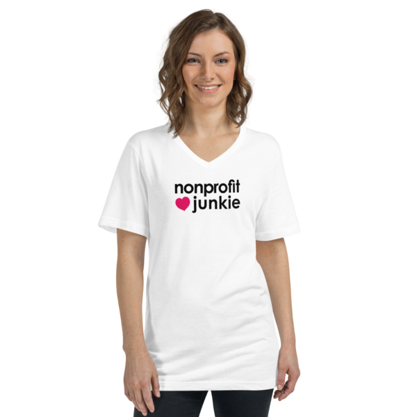 Unisex white v neck t shirt, black text on one side says nonprofit junkie in regular arial font next to a pink heart on a woman