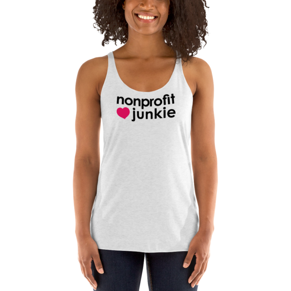 Womens heather white racerback tank, black text on one side says nonprofit junkie next to a pink heart, on a woman