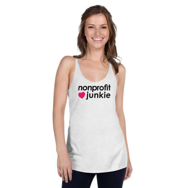 Womens heather white racerback tank, black text on one side says nonprofit junkie next to a pink heart, on a woman