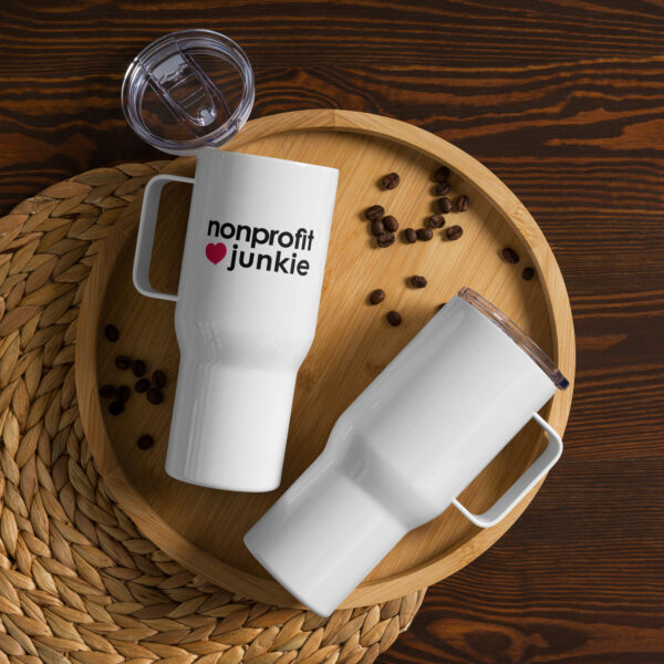 White travel mug with black text that says nonprofit junkie in regular arial like font next to a pink heart