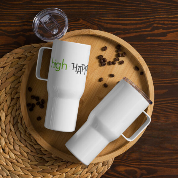 White travel mug with handle, green and black text on one side says high + happy in regular arial like font