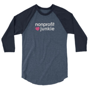 Navy 3 4th sleeve raglan shirt, heather denim in middle, white text on one side says nonprofit junkie next to a pink heart