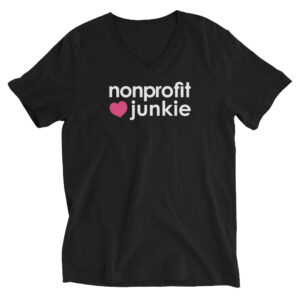 Unisex black v neck t shirt, white text on one side says nonprofit junkie in regular arial font next to a pink heart