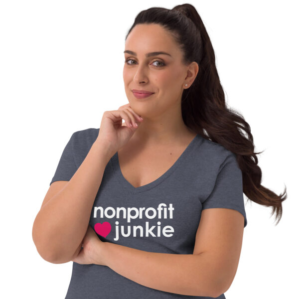 Womens heather navy recycled v neck t shirt, white text on one side says nonprofit junkie in regular arial font next to a pink heart on a woman